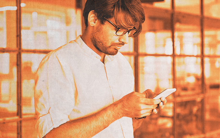 man with glasses texting on phone